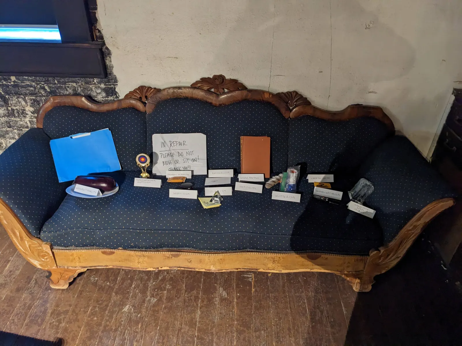 The Ideology Altar arranged across a couch, with objects representing ideologies and a labeled tent sign in front of each one.
