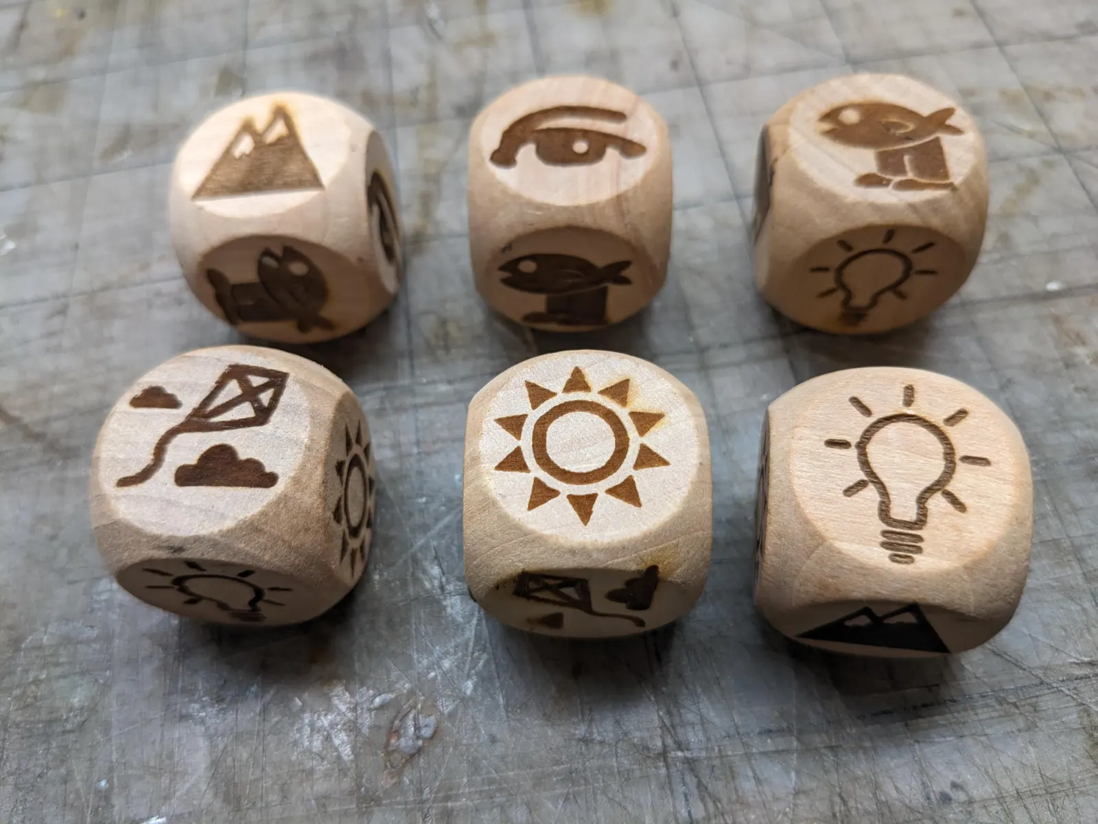 Six wooden dice engraved with symbols representing textures of the complete stance.